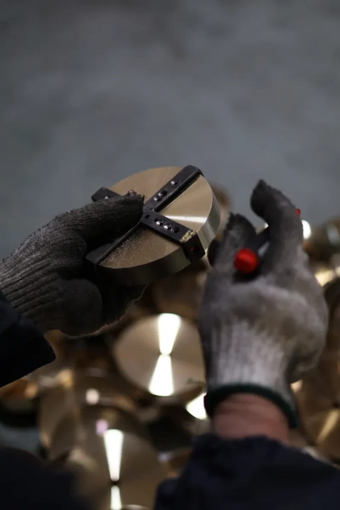 A gloved worker checks a circular metal component with a gauge